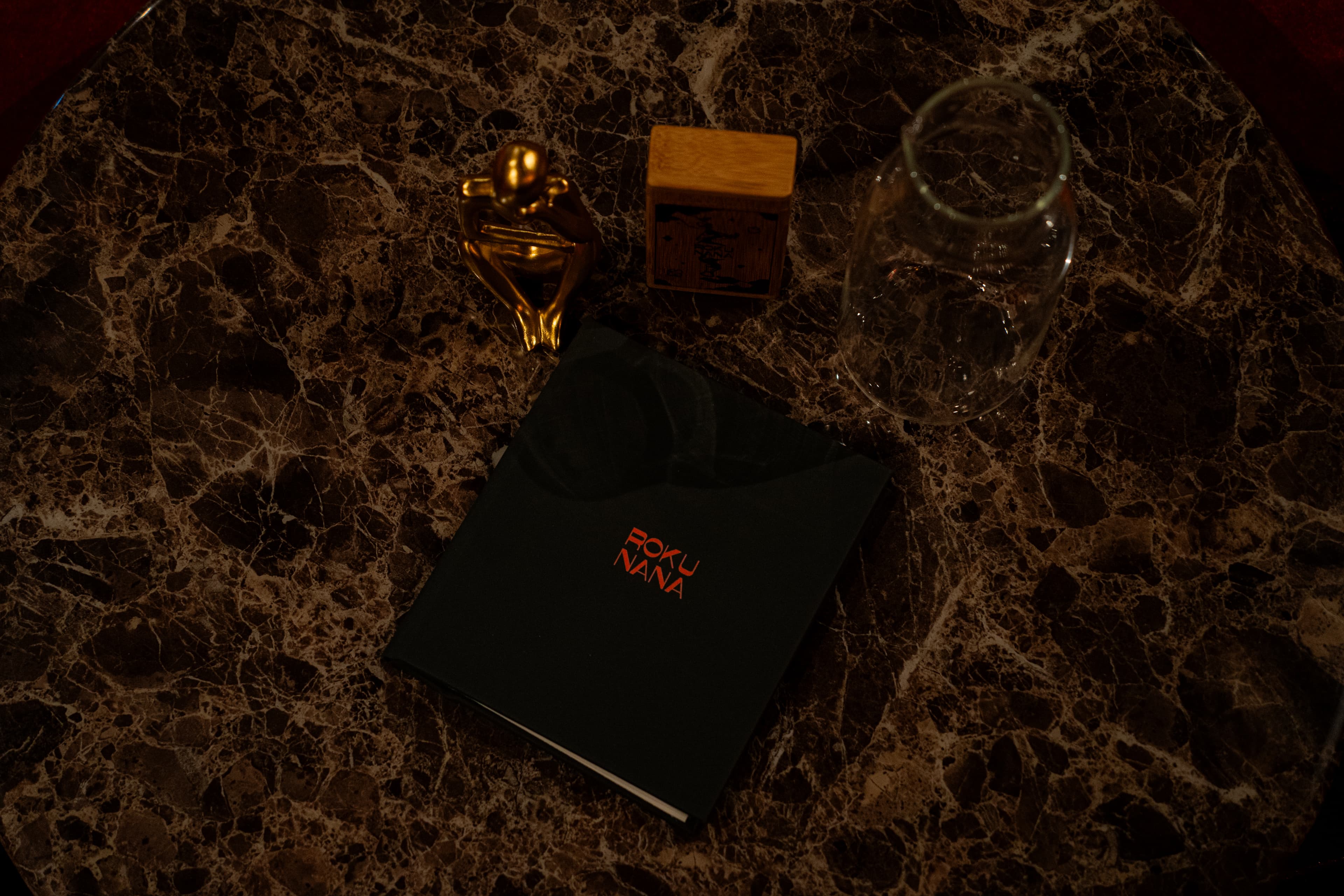Roku Nana menu on marble table with golden figurine