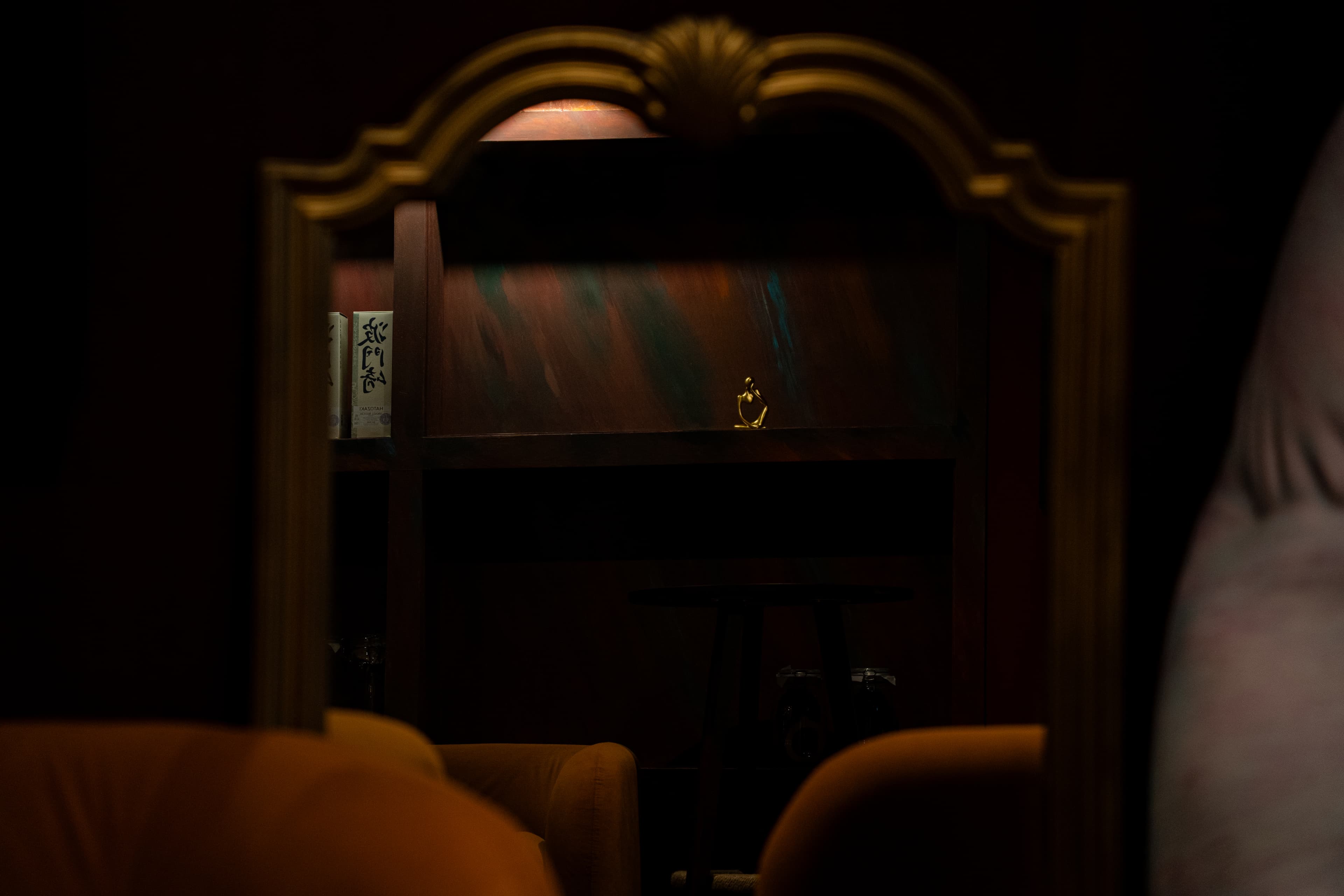 Mirror reflection showing gold figurine and back shelf detail at RokuNana NYC